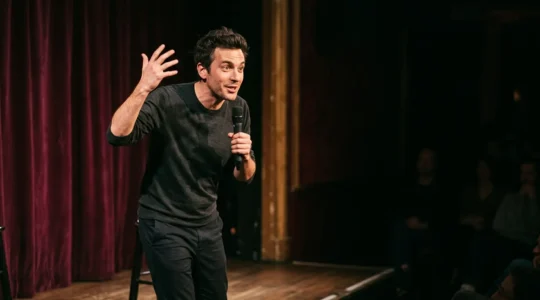 Artiste comique sur scène captivant le public avec un geste théâtral dans une atmosphère intimiste