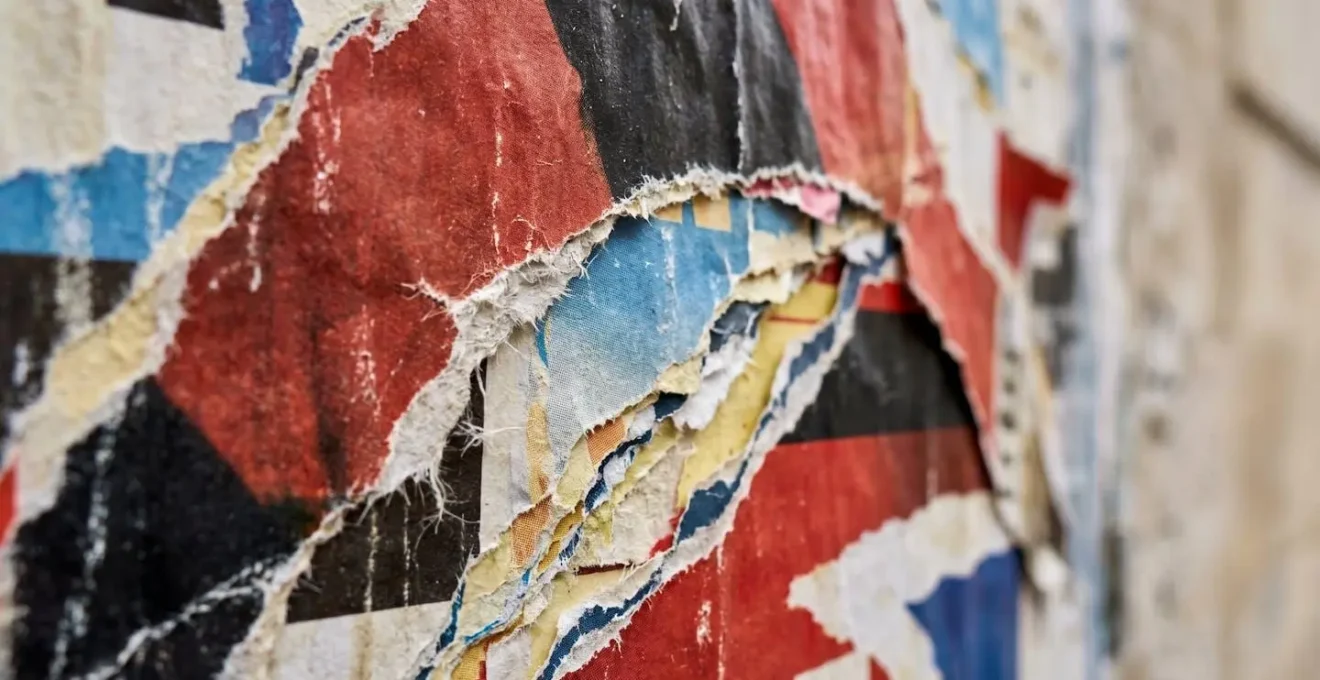 Mur d'affichage urbain parisien avec affiches de spectacles superposées et textures de rue